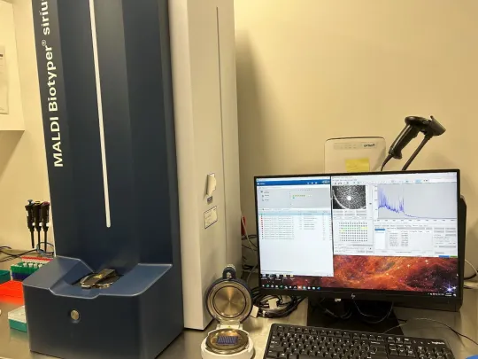 Photo of lab desktop with MALDI ToF machine and desktop computer